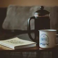 French press z kawą, kubek z napisem "Coffee" i książka o kawie. Idealny zestaw, by dowiedzieć się, ile kawy do french press.
