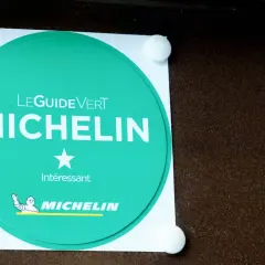 Adesivo verde Michelin con una stella, che indica un riconoscimento "Interessante" per un ristorante.