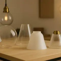 Varias pantallas de lámpara, incluyendo una de tulipa, sobre una mesa de madera.