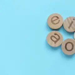 Drewniane krążki z literami: a, e, i, o, u. Uczymy się, jakie mamy samogłoski.