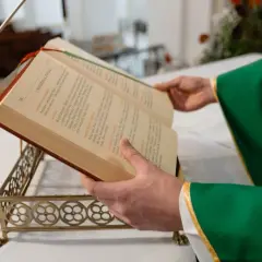 Kapłan w zielonej szacie czyta z księgi liturgicznej. Zastanawiasz się, ile trwa msza niedzielna?