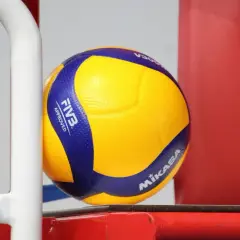 Żółto-niebieska piłka Mikasa V300, zatwierdzona przez FIVB, gotowa do gry na boisku.