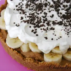 En krämig banoffee paj med lager av banan, kolasås och vispad grädde, toppad med chokladströssel.