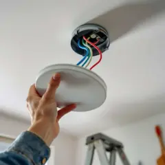 Main tenant installe une nouvelle pose lampe au plafond, connectant les fils colorés.