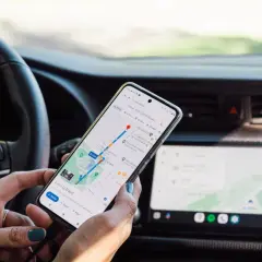 Ręce trzymają telefon z nawigacją, aby uniknąć mandatu za telefon podczas jazdy.