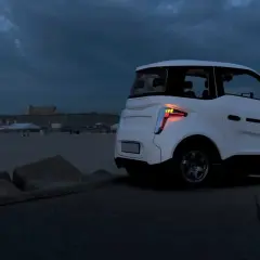 Biały, rosyjski samochód elektryczny stoi na nadmorskiej promenadzie o zmierzchu.