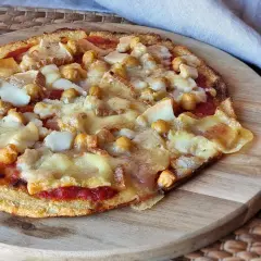 Pizza sin queso con garbanzos y trozos de queso derretido sobre una base crujiente.