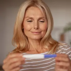 Bea Szenfeld, med ett leende, håller ett graviditetstest.