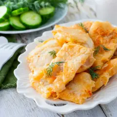 Deliciosa merluza rebozada, crujiente por fuera y tierna por dentro, adornada con eneldo fresco. Acompañada de rodajas de pepino.
