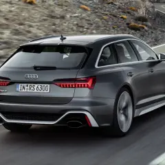 El Audi RS6 ranchera gris oscuro acelera por una carretera sinuosa entre montañas.