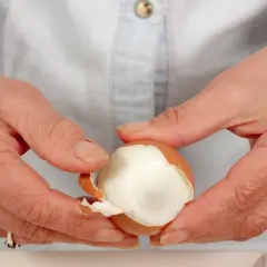Dłonie obierają jajko na twardo. Czy jajka podnoszą cholesterol? To pytanie nurtuje wiele osób, ale współczesne badania pokazują, że umiarkowane spożycie jajek jest bezpieczne.