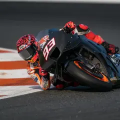 Piloto de MotoGP inclinado en curva, con su moto negra y naranja. La potencia de cuántos caballos tiene una MotoGP es asombrosa.