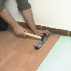 Układanie podłogi pływającej co to? Montaż paneli laminowanych przy użyciu młotka i listwy dociskowej.