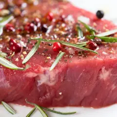 Un morceau de viande rouge, assaisonné de poivre rose, de romarin et d'épices, prêt à devenir l'une des 10 meilleurs viandes du monde.