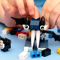 Kinderhände bauen mit bunten Klemmbausteinen einen Fledermaus-Charakter. Ein beliebter Klemmbaustein Hersteller ermöglicht kreativen Spielspaß.