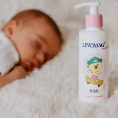 Śpiące dziecko obok butelki oliwki dla noworodka Linomag.