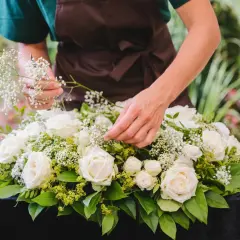 Tworzenie wiązanki na cmentarz: białe róże, gipsówka i zieleń tworzą elegancką kompozycję.