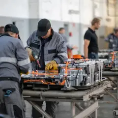 Pracownicy montują moduły baterii do pojazdów elektrycznych. To przyszłość elektromobilności i praca dla wielu.