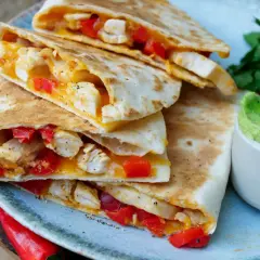 Leckeres Quesadillas Rezept: goldbraune Tortillas gefüllt mit Hähnchen, roter Paprika und geschmolzenem Käse, serviert mit Guacamole.