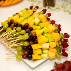 Kolorowa deska owoców na imprezę: szaszłyki z winogron, melona, kiwi, ananasa i malin.