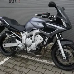 Szary motocykl Yamaha FZ6 z czarnymi akcentami, gotowy do jazdy po miejskich ulicach.