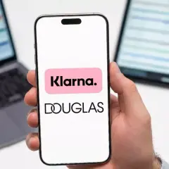 Dłoń trzyma smartfon z logo Klarna i Douglas. To ułatwia zakupy, jak douglas paypo.