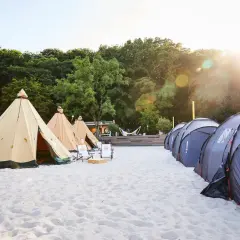 Zelte am Strand, bereit für den Summerjam Comfort Camp. Sonnenschein und entspannte Atmosphäre.