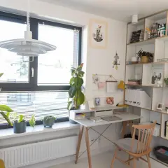 Jasny gabinet w domu z biurkiem, regałem pełnym książek i roślin. Inspiracje do aranżacji domowego biura.
