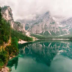 Spokojne Lago di Braies odbija majestatyczne góry i zielone lasy. Ścieżka wije się wzdłuż skalistego brzegu.