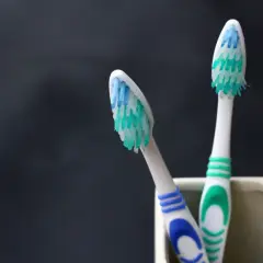 Dwie zużyte szczoteczki do zębów w kubeczku. Pamiętaj, co ile wymieniać szczoteczkę do zębów, by dbać o higienę jamy ustnej.