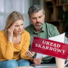 Para martwi się o pieniądze z wesela na konto. Na stole leży tabliczka "Urząd Skarbowy", a kobieta trzyma się za głowę.