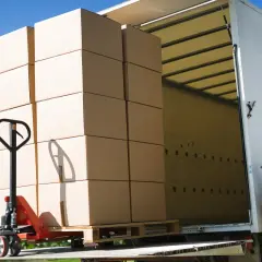 Pracownik ładuje paletę z kartonami do ciężarówki. Efektywny transport drobnicowy Polska.