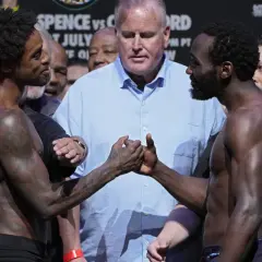 Terence Crawford and Errol Spence Jr. shake hands before their fight, surrounded by officials and a crowd.