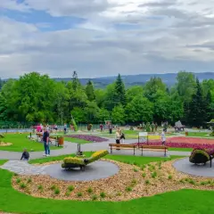 Kolorowy park z rzeźbami z kwiatów i zieleni. W tle las i wzgórza. Sprawdź góra parkowa cennik, by zaplanować wizytę.