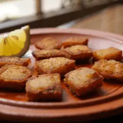 Bocaditos dorados de bacalao rebozado, crujientes y listos para disfrutar, acompañados de una rodaja de limón fresco.
