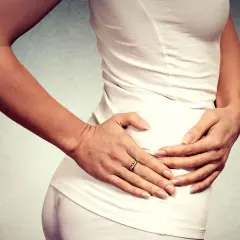 Donna con le mani sull'anca, che esprime dolore anca e ginocchio a riposo.