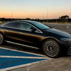 Elegancki, czarny Mercedes EQS na pustym parkingu o zachodzie słońca. Luksusowa limuzyna elektryczna prezentuje swoje aerodynamiczne linie.