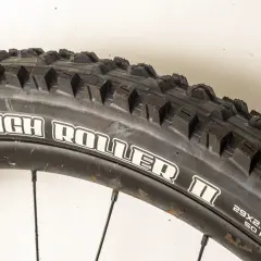 Close-up of a Maxxis High Roller II tire, ready for a review. Its aggressive tread promises excellent grip on challenging trails.