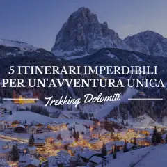 Paesaggio invernale con villaggio illuminato e montagne innevate. 5 itinerari imperdibili per un'avventura unica: Trekking Dolomiti.