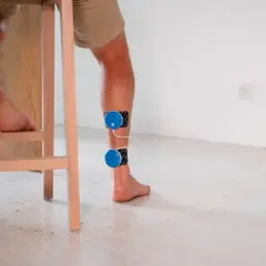 Un coureur souffrant de douleur au tendon d'Achille utilise un appareil d'électrostimulation pour soulager sa blessure.