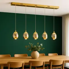 Eleganckie, złote lampy w kształcie jajek świeci pod sufitem nad drewnianym stołem.