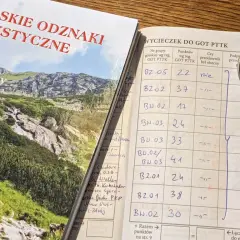 Książeczka GOT PTTK z wpisami wycieczek i odznaką przodownika.