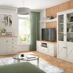 Jasny salon w stylu skandynawskim. Białe meble z drewnianymi blatami, zielona kanapa, jasne zasłony i obraz z ptakami.