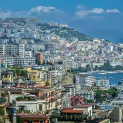 Panorama di Napoli con case colorate, il Vesuvio sullo sfondo e yacht nel porto. Come si dice in napoletano? "Napule è!