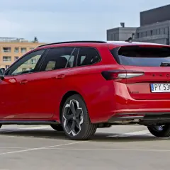 Czerwone, najładniejsze kombi Skoda Superb na parkingu. Eleganckie linie i nowoczesny design.