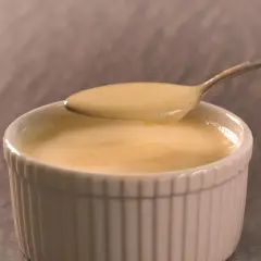 Cremige Vanillesauce, frisch zubereitet, auf einem Löffel. Perfekt zum vanillesauce selber machen.