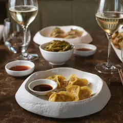 Ristoranti stellati Milano: un'esperienza culinaria con ravioli dorati, edamame e vino bianco.