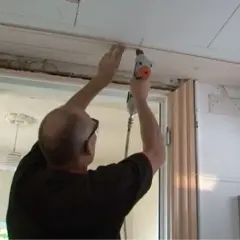 Man byter innertak med tryckluftspikpistol. Träpanel monteras längs takkanten.