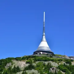 Wieża telewizyjna Ještěd, jedna z głównych libereckich atrakcji, góruje nad zielonym wzgórzem.