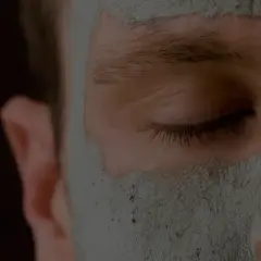 Närbild på ett ansikte med en lermask som rengör porerna.